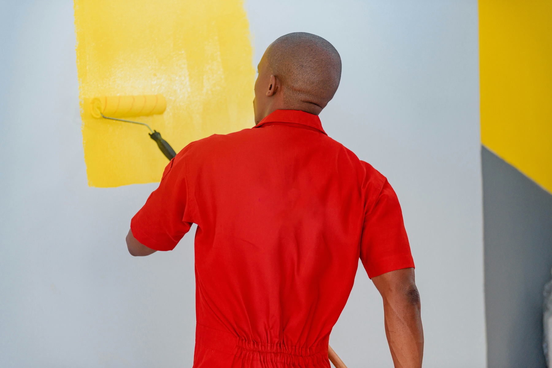 Commercial painter rolling yellow paint on a wall