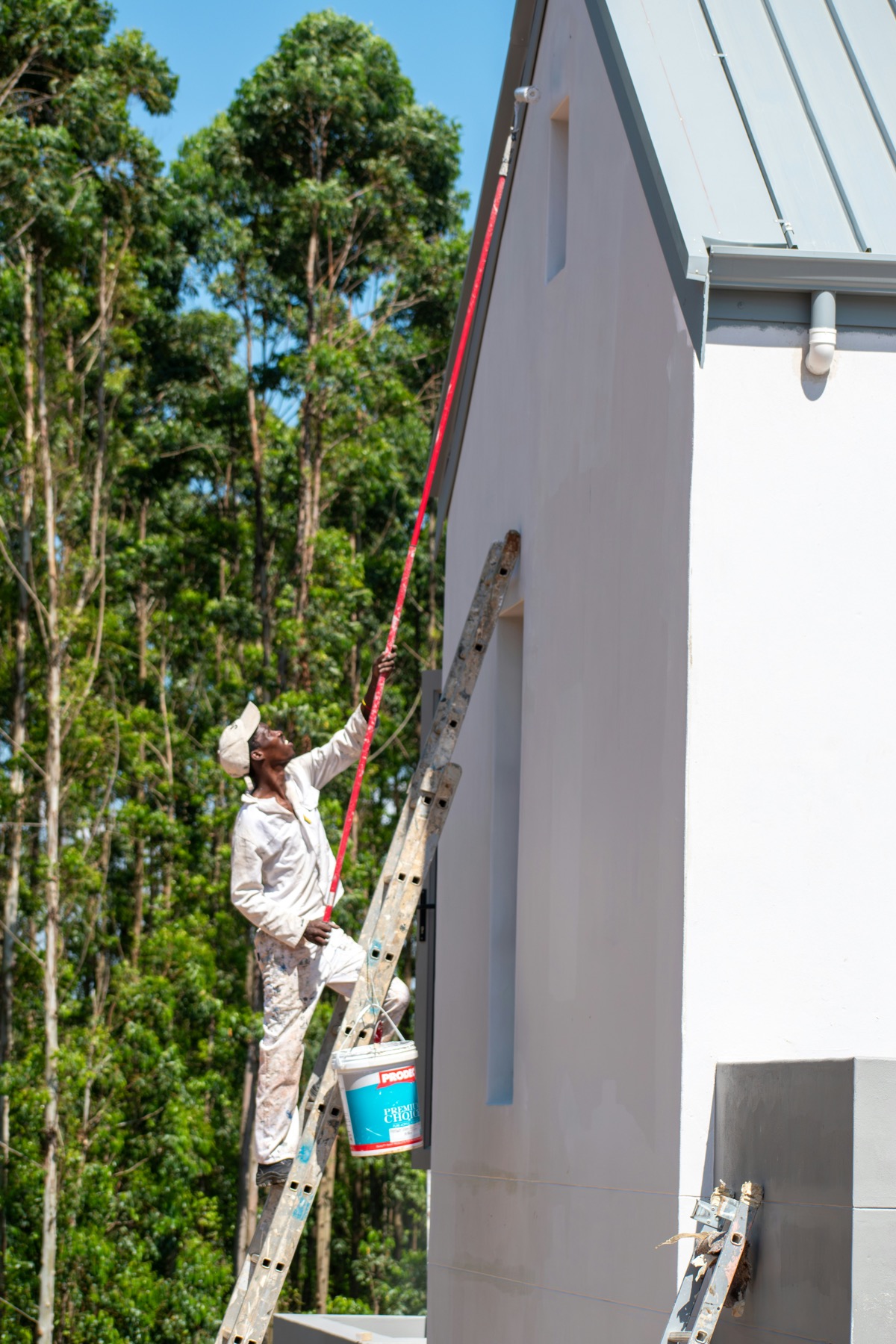 Exterior painter working on a white house wall