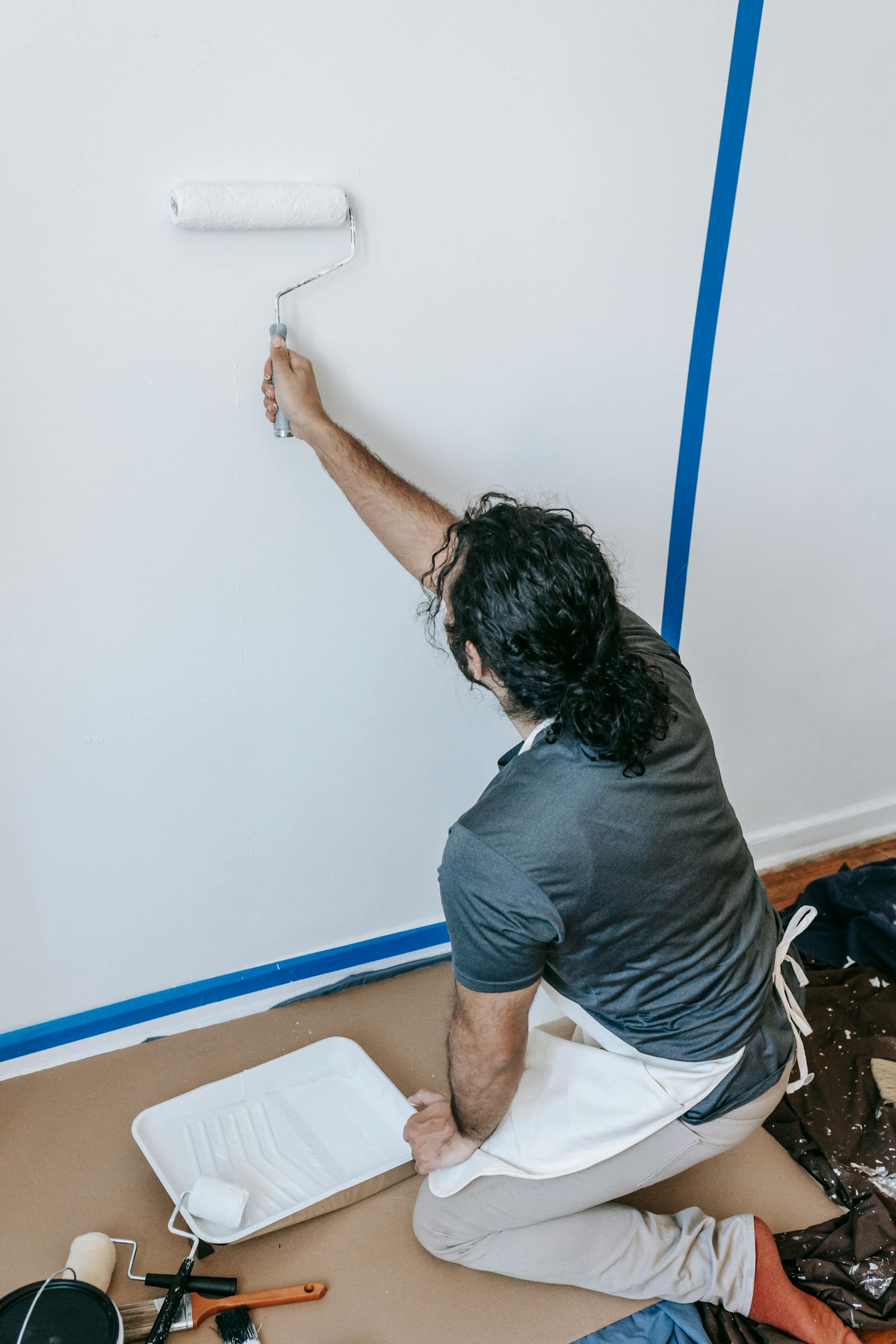 Painter applying white paint to an interior wall